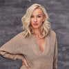 Woman wearing a beige sweater against a gray textured background