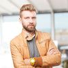 Man wearing a tan jacket with a blurred indoor background